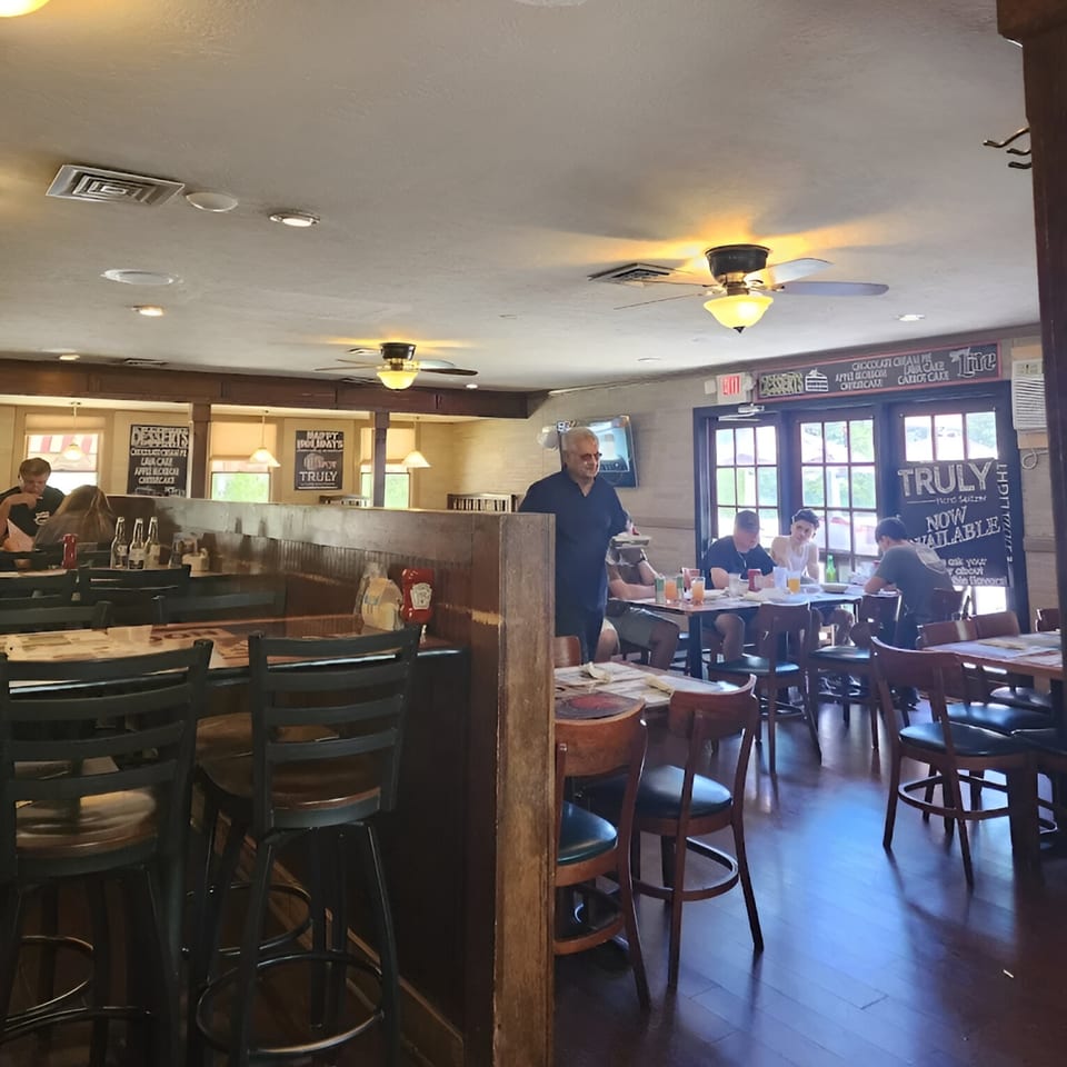 The Spot Cafe interior with patrons dining at tables and a server carrying food.